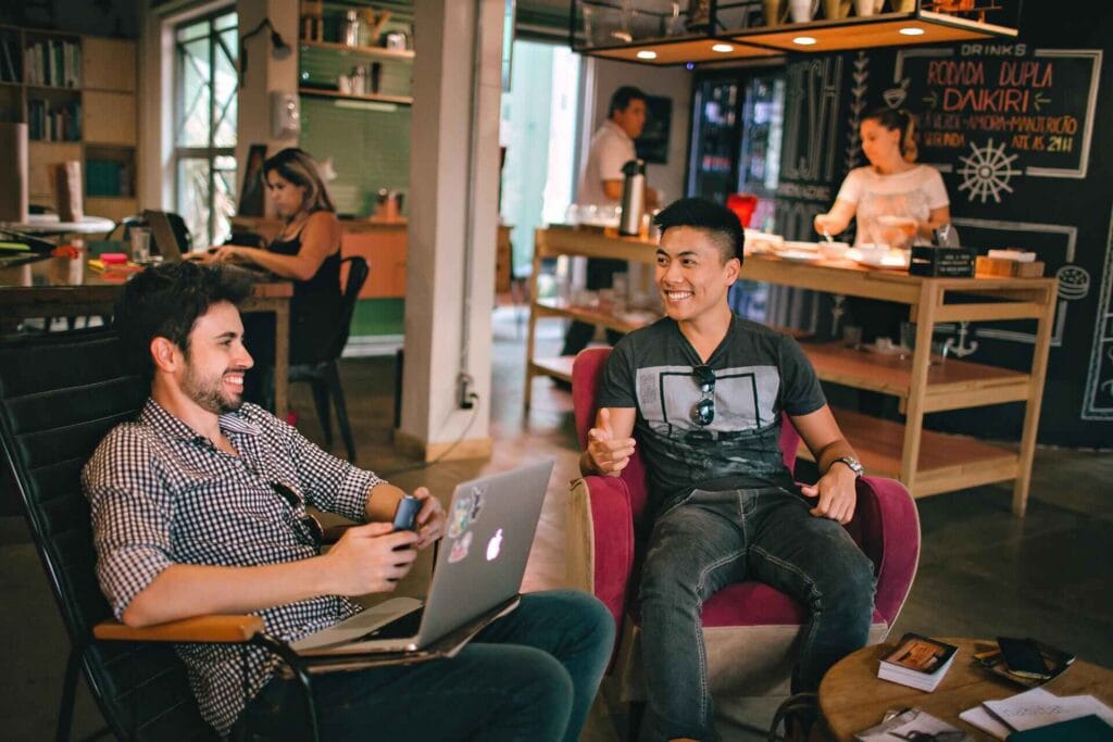 People sitting together, talking and working on their laptops in a shared workspace.